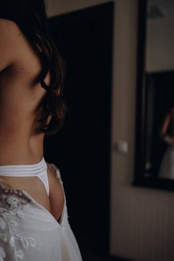 Dikiz manzaralı genç güzel gelin odasında gelinliğini giyiyor.. 