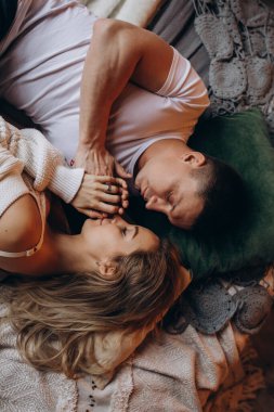 Güzel, mutlu, genç bir çift yatakta birlikte yatıyor.        