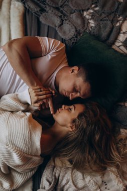 Birbirine aşık güzel genç çiftin yatakta yan yana yatışının üst görüntüsü.