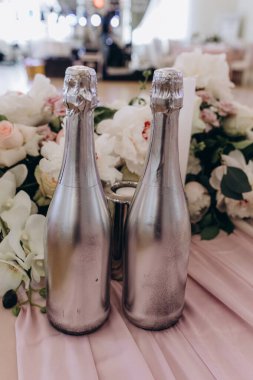 Masada güzel çiçekli iki gümüş şampanya şişesi