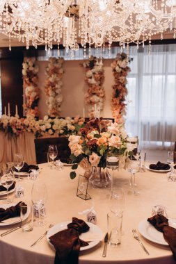 Düğün resepsiyonunda çiçeklerle süslenmiş zarif sofra manzarası.         