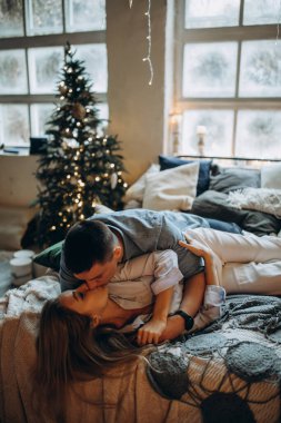 Genç çift yatakta yatıyor, stüdyo Noel dekoruyla 