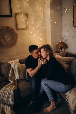 Güzel, mutlu, genç bir çift Noel dekoruyla rahat bir odada aşık.                    