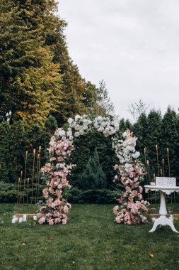 Açık hava düğün töreni için güzel çiçeklerle süslenmiş zarif kemer.       