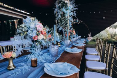 Düğün resepsiyonunda çiçeklerle süslenmiş zarif sofra manzarası.         