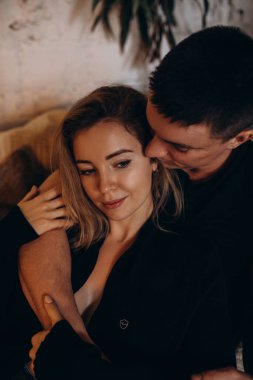 Güzel, mutlu, genç bir çift evde birbirine sarılıyor.     