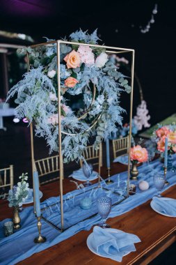 Düğün resepsiyonunda çiçeklerle süslenmiş zarif sofra manzarası.         