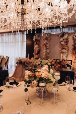 Düğün resepsiyonunda çiçeklerle süslenmiş zarif sofra manzarası.         