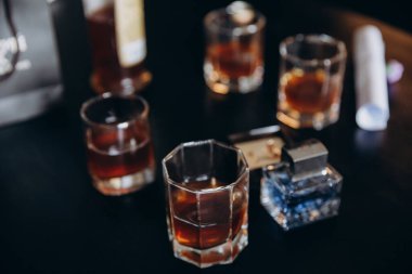 Parfüm şişesi ve bardaklar masada.