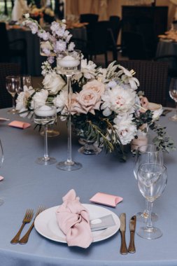 Düğün resepsiyonunda çiçeklerle süslenmiş zarif sofra manzarası.         