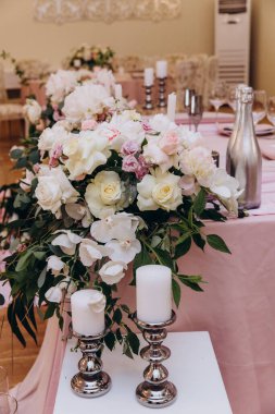 Düğün resepsiyonunda çiçeklerle süslenmiş zarif sofra manzarası.         