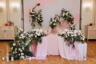 Düğün resepsiyonunda çiçeklerle süslenmiş zarif sofra manzarası.         