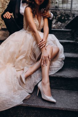 Gelinlik giymiş, yakışıklı damat merdivenlerde otururken çekilmiş bir fotoğraf.