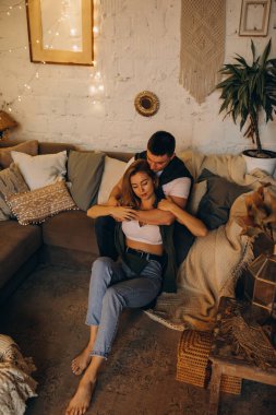 Güzel, mutlu, genç bir çift Noel dekoruyla rahat bir odada aşık.                    