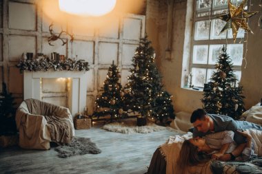 Genç çift yatakta yatıyor, stüdyo Noel dekoruyla 