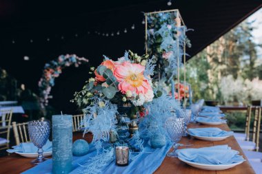 Düğün resepsiyonunda çiçeklerle süslenmiş zarif sofra manzarası.         