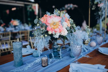 Düğün resepsiyonunda çiçeklerle süslenmiş zarif sofra manzarası.         