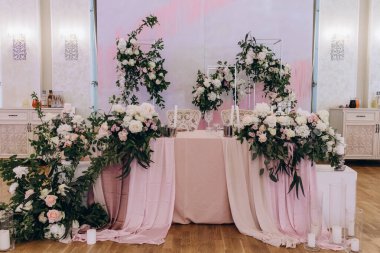 Düğün resepsiyonunda çiçeklerle süslenmiş zarif sofra manzarası.         