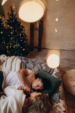 Güzel, mutlu, genç bir çift Noel dekoruyla rahat bir odada aşık.                    
