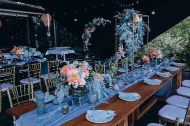 Düğün resepsiyonunda çiçeklerle süslenmiş zarif sofra manzarası.         