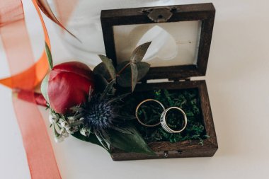 Tahtada kırmızı gül çiçekli güzel alyanslar.