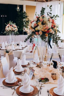 Düğün resepsiyonunda çiçeklerle süslenmiş zarif sofra manzarası.         