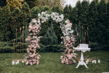 Açık hava düğün töreni için güzel çiçeklerle süslenmiş zarif kemer.       