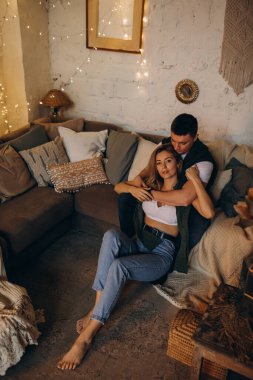 Güzel, mutlu, genç bir çift Noel dekoruyla rahat bir odada aşık.                    