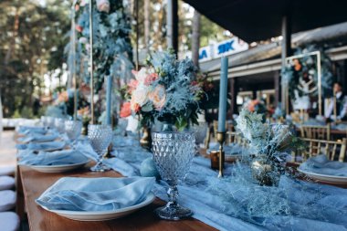 Düğün resepsiyonunda çiçeklerle süslenmiş zarif sofra manzarası.         