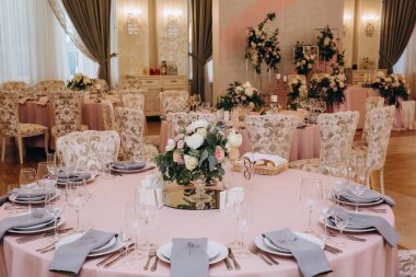 Düğün resepsiyonunda çiçeklerle süslenmiş zarif sofra manzarası.         