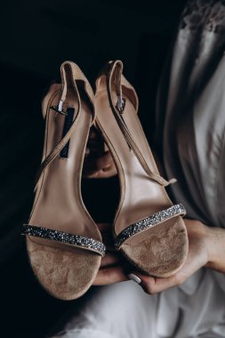 Gelin ellerinin düğün ayakkabılarını tutuş görüntüsünü kapat.