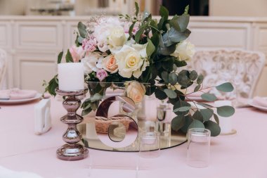 Düğün resepsiyonunda çiçeklerle süslenmiş zarif sofra manzarası.         