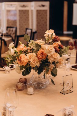 Düğün resepsiyonunda çiçeklerle süslenmiş zarif sofra manzarası.         