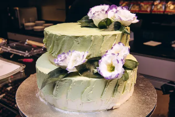 Çiçeklerle süslenmiş lezzetli düğün pastasının yakın çekimi.              