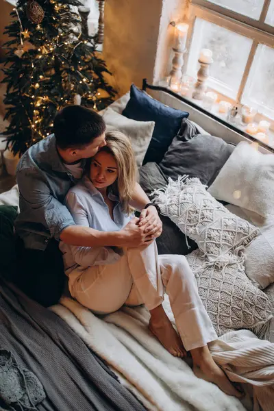 Genç çift yatakta yatıyor, stüdyo Noel dekoruyla 