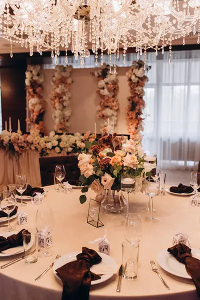 Düğün resepsiyonunda çiçeklerle süslenmiş zarif sofra manzarası.         