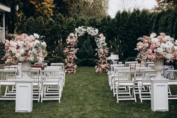 Açık hava düğün töreni için güzel çiçeklerle süslenmiş zarif kemer.       