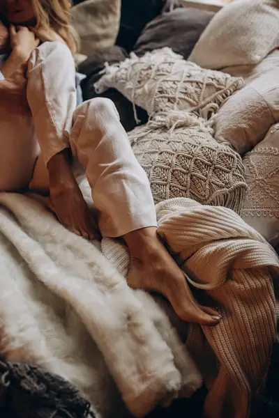 Beyaz örgü süveter ve kot pantolonlu genç bir kadın evde yatıyordu.