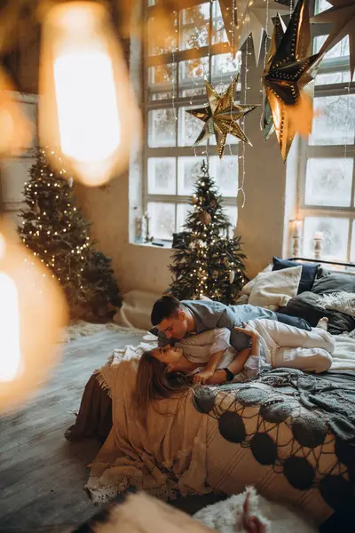Genç çift yatakta yatıyor, stüdyo Noel dekoruyla 