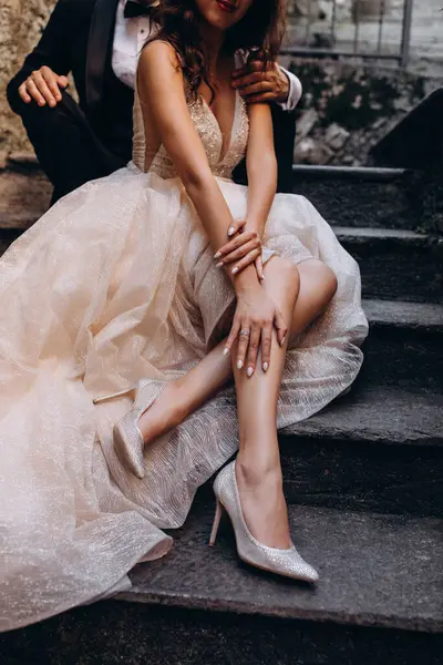 Gelinlik giymiş, yakışıklı damat merdivenlerde otururken çekilmiş bir fotoğraf.