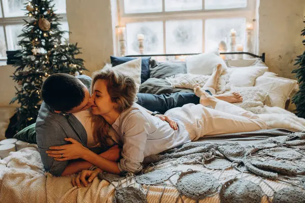 Genç çift yatakta yatıyor, stüdyo Noel dekoruyla 