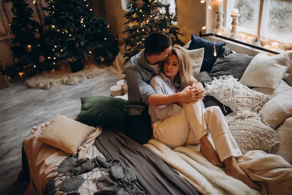 Genç çift yatakta yatıyor, stüdyo Noel dekoruyla 