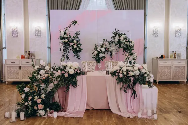 Düğün resepsiyonunda çiçeklerle süslenmiş zarif sofra manzarası.         