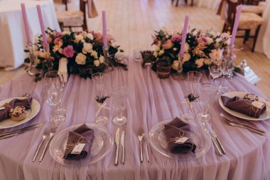 Düğün resepsiyonunda çiçeklerle süslenmiş zarif sofra manzarası.         