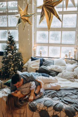 Genç çift yatakta yatıyor, stüdyo Noel dekoruyla 