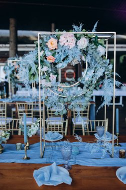 Düğün resepsiyonunda çiçeklerle süslenmiş zarif sofra manzarası.         