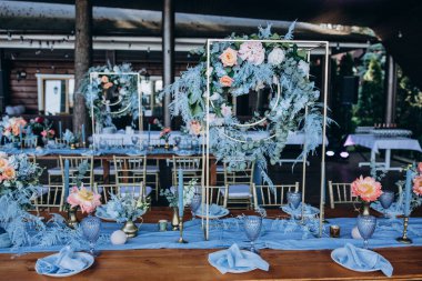 Düğün resepsiyonunda çiçeklerle süslenmiş zarif sofra manzarası.         