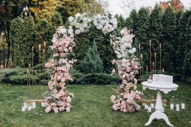 Açık hava düğün töreni için güzel çiçeklerle süslenmiş zarif kemer.       