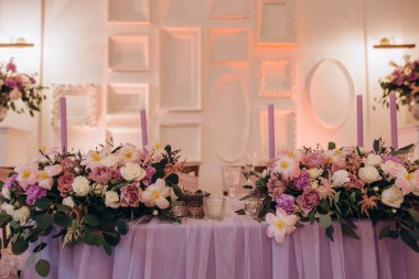 Düğün resepsiyonunda çiçeklerle süslenmiş zarif sofra manzarası.         