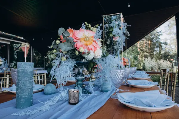 Düğün resepsiyonunda çiçeklerle süslenmiş zarif sofra manzarası.         
